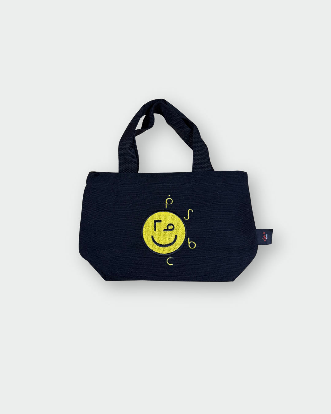 Black Mino giizhigad tote bag with a yellow smiley face design on a white background