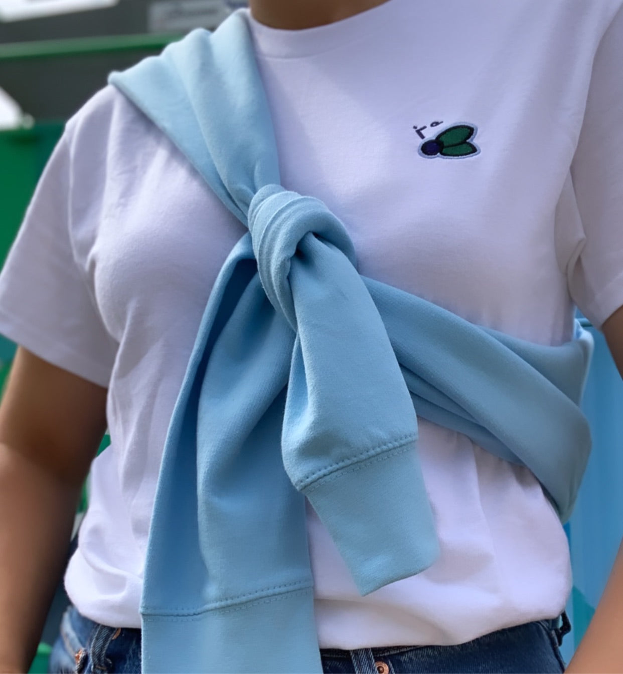 Woman wearing shirt with blueberry and sweater tied around her chest