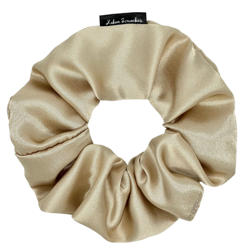 A beige satin scrunchie against a white background.