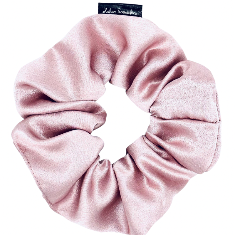 A pink satin scrunchie with a rose gold color.