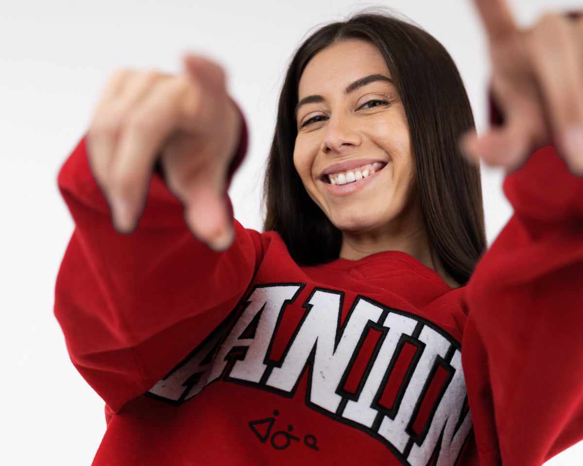 Person wearing a red sweatshirt with text, making a peace sign gesture.