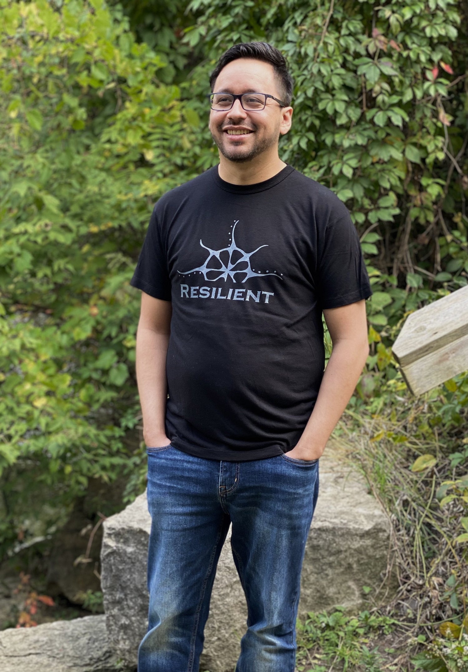 Black bamboo unisex t-shirt on a man with a stylized rising sun graphic above the word &quot;Reslilient&quot;