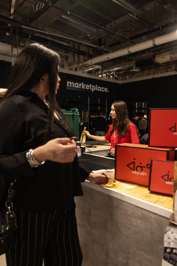 Woman interacting with a counter at Aaniin Apparel, while one of the staff pours her a beverage during an influencer marketing event.. Photo by Benjamin's Agency Inc.