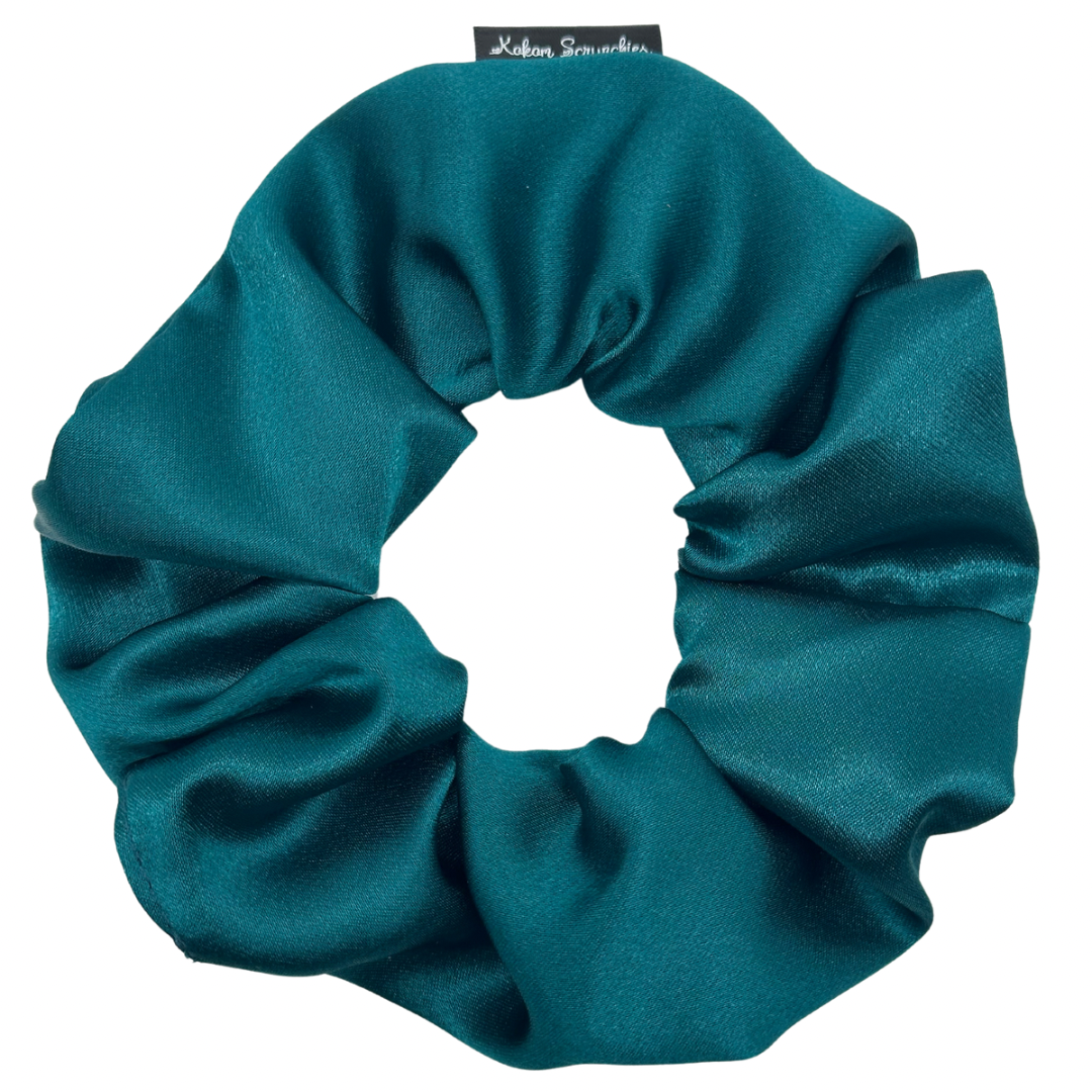 A green satin scrunchie against a white background.