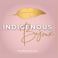 Indigenous Bijoux HANDMADE logo in a square format. A gold gradient feather sits above white serif font with a black blurred glow in all caps and brown-gold sans-serif cursive font finishes the brand title. Below we see in capital white serif text 'handmade' with a gold square border to the right. The brand has Métis & Cree made beaded jewelry with fringe, hexagonal, triangle, and tipi styled earrings.