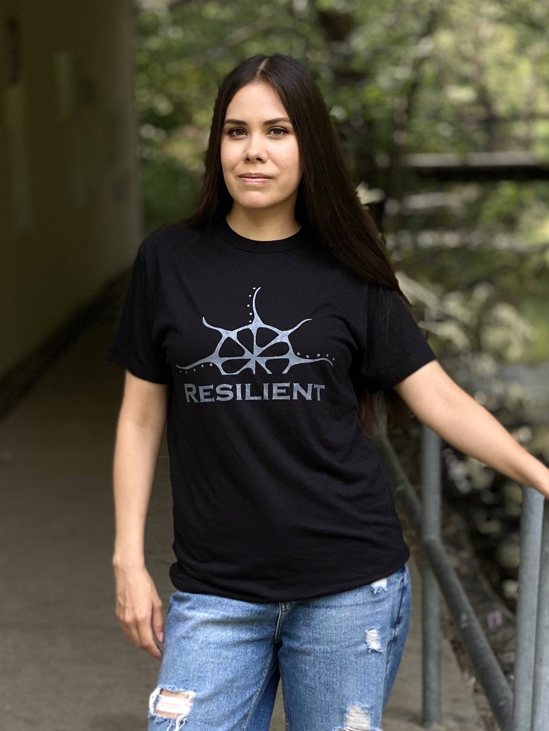 A woman wearing a black t-shirt with the word &quot;Resilient&quot; under a stylized rising sun