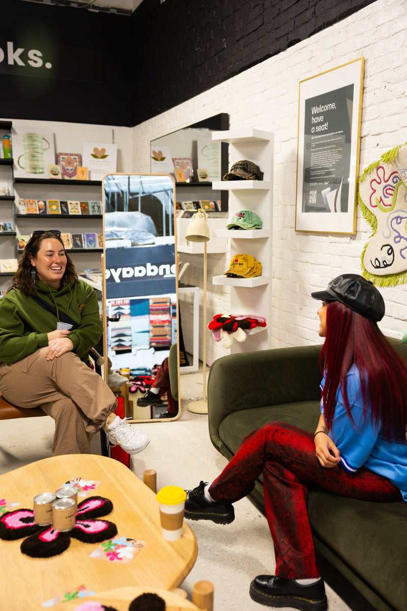 Two people sitting on a couch in a store with shelves and decor in the background.