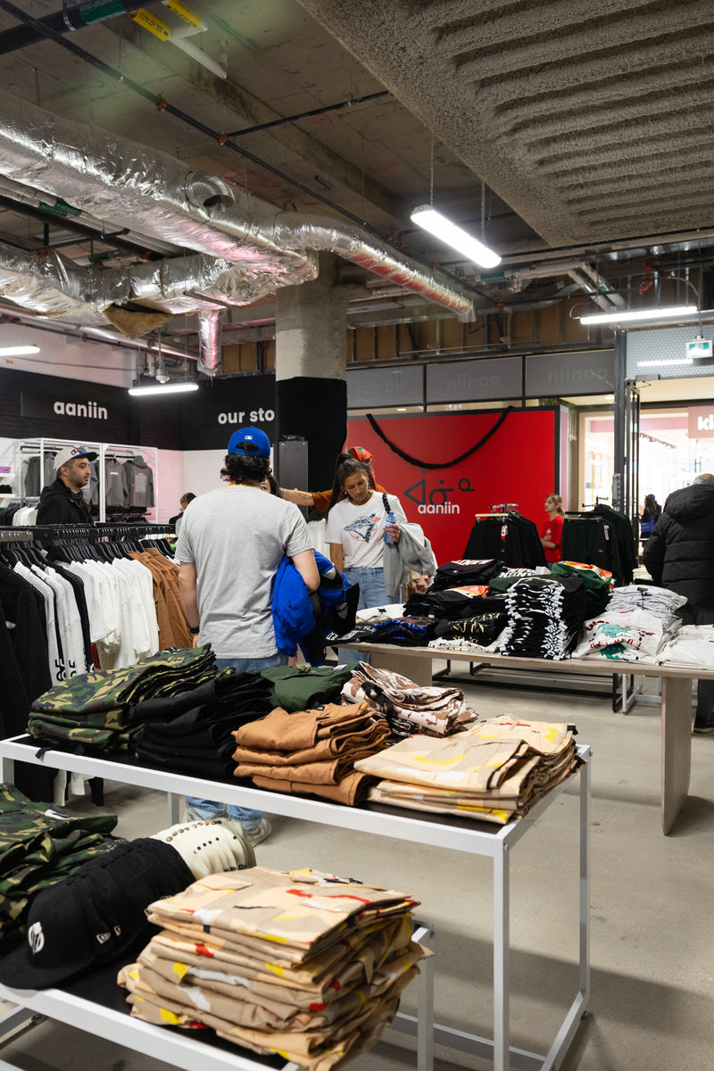 Retail store interior with clothing displays and customers.
