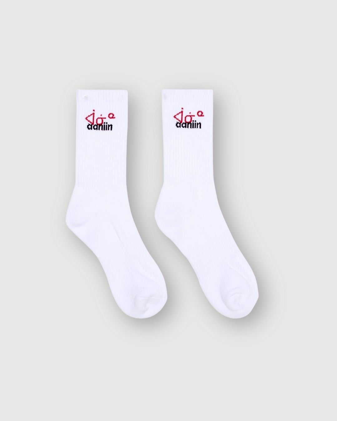 White crew socks with the aaniin red syllabics and black text along the ankle.