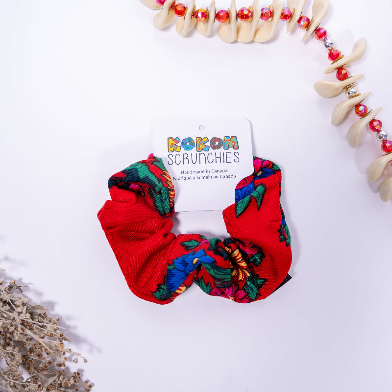 Red scrunchie with colorful patterns on a white background with &