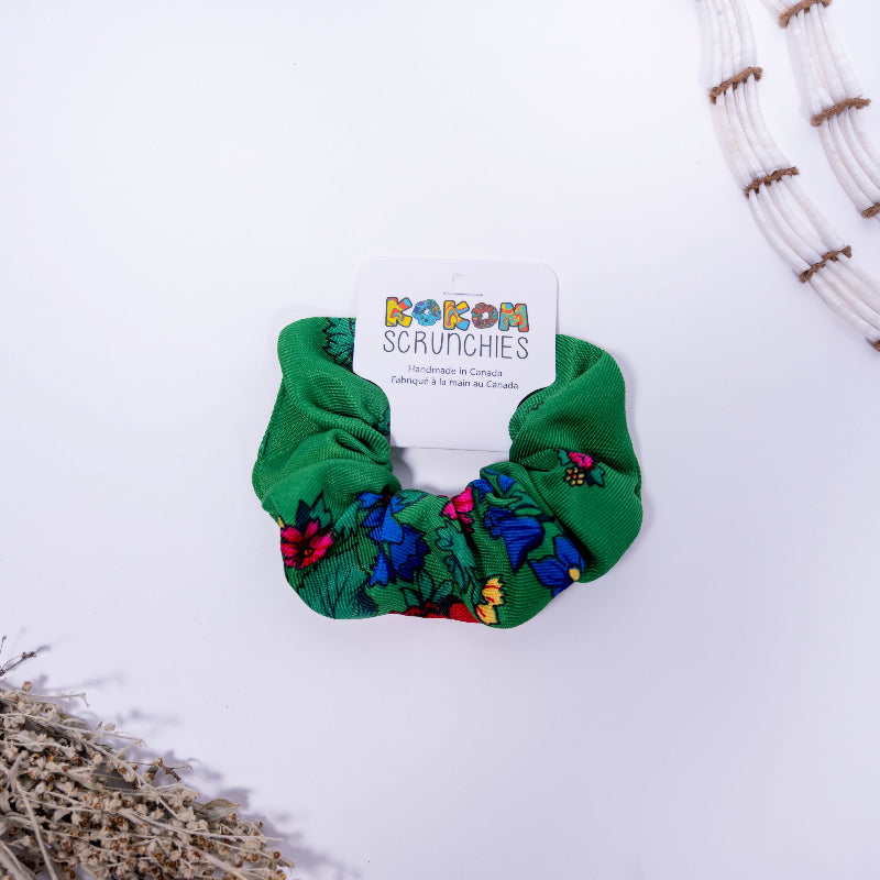 Green scrunchie with floral pattern on a white background, featuring a &