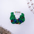 Green scrunchie with floral pattern on a white background, featuring a &