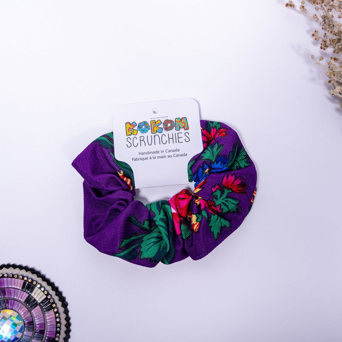 purple scrunchie with floral patterns on a white background, featuring a &