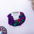 purple scrunchie with floral patterns on a white background, featuring a &