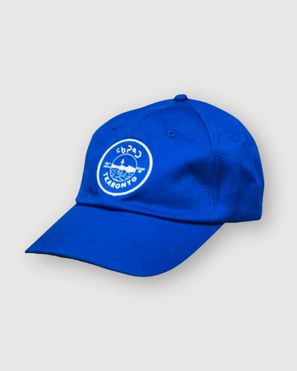Blue aaniin dad cap, side view, with the tkaronto crest on it in white to resemble the Toronto sports teams that use white and blue